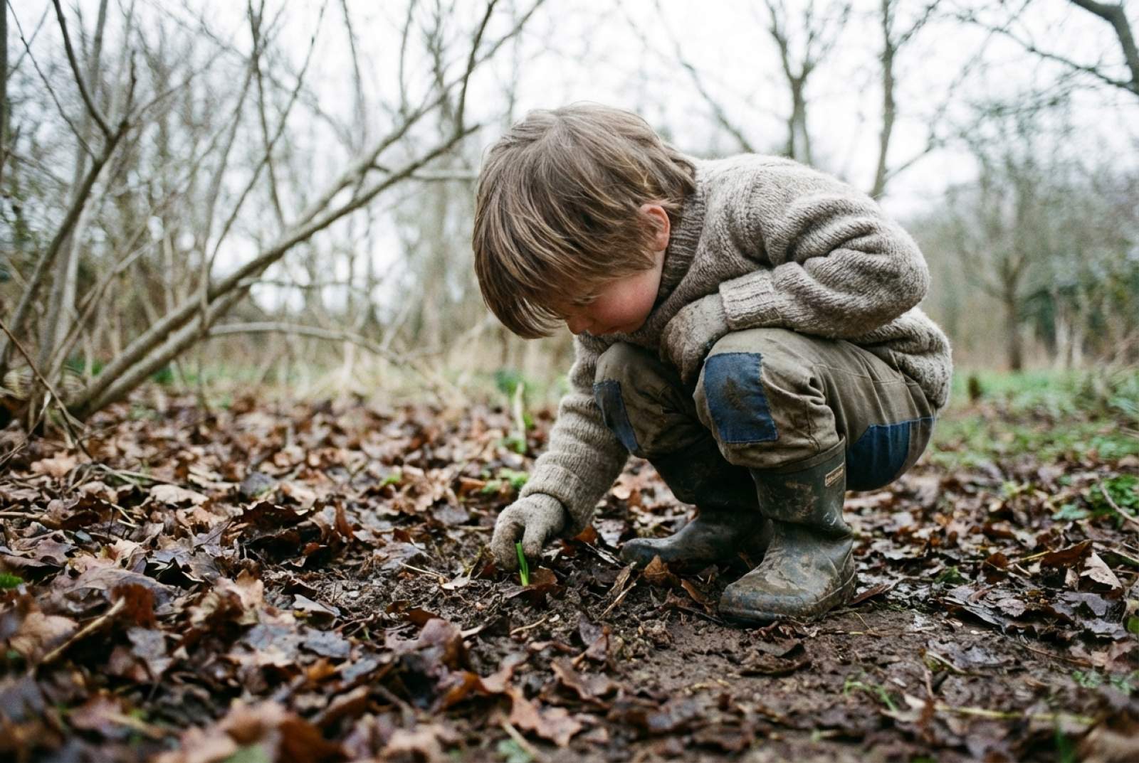 Ein kleiner Junge findet eine versteckte Blumenknospe im Laub.