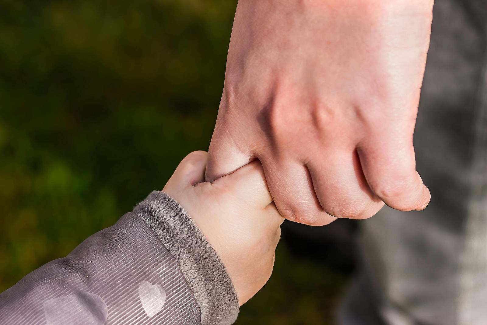 Die Hand eines Kindes hält die Hand eines Erwachsenen.