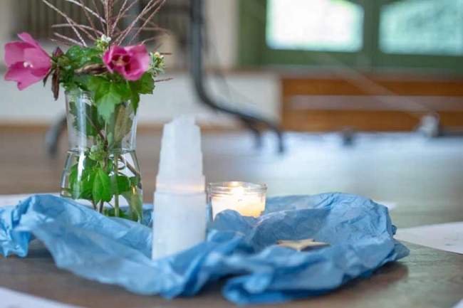 Kinderastrologie Ausbildung – Vase mit Blumen, Kerze und Kristall auf blauem Tuch als Ritual-Dekoration