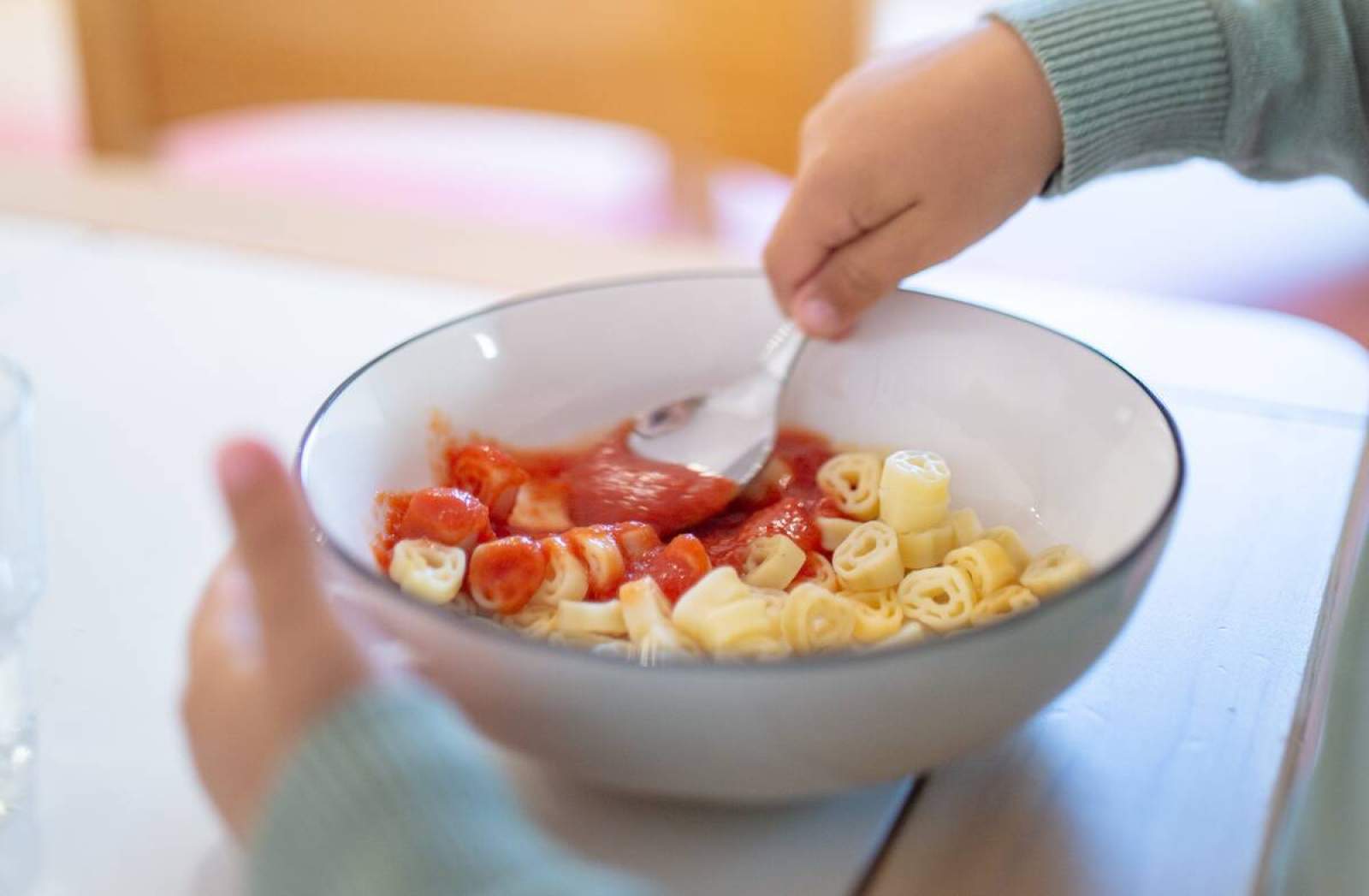 Kind isst Nudeln mit Tomatensoße.
