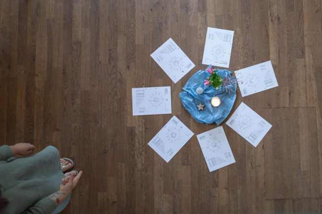 Jahreskreis – ausgelegte Arbeitsblätter im Kreis mit Kerze, Blumen und spiritueller Dekoration