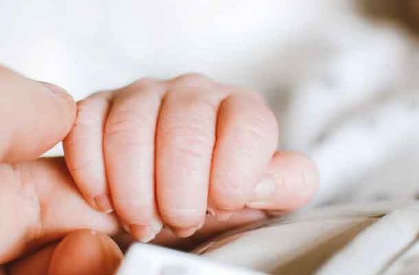 Das Bild zeigt ein Baby das eine Hand hält und soll symbolisieren, welche sinnvollen Geschenkideen es zur Geburt gibt